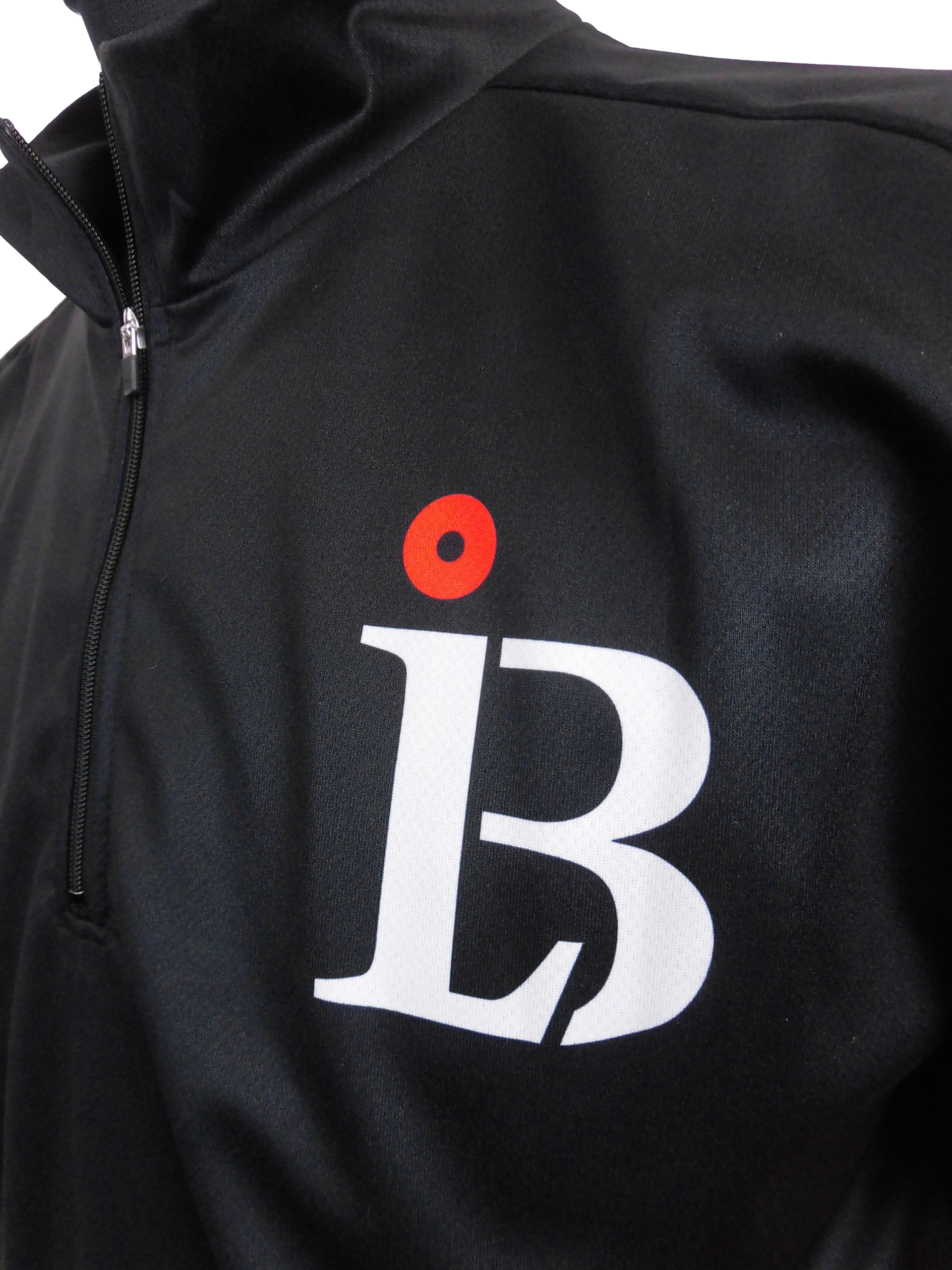 Close-up of a black zip-up jacket showing a bold white letter with a red dot logo on the chest area.