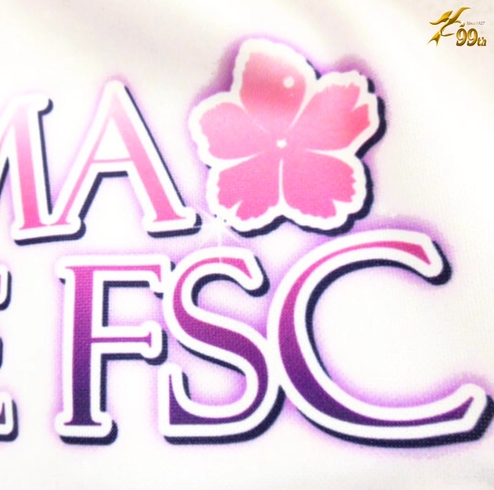 Close-up of a pink cherry blossom graphic beside purple-outlined letters forming a logo, with a small gold badge in the corner.