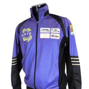 Purple and black zip-up athletic jacket on a mannequin, featuring sponsor logos on the chest and one sleeve.
