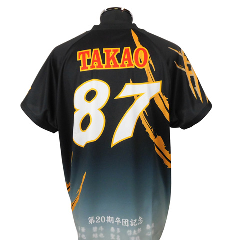 Back view of a black sports jersey with the name TAKAO and large white 87, orange accents and a gradient blue lower hem.