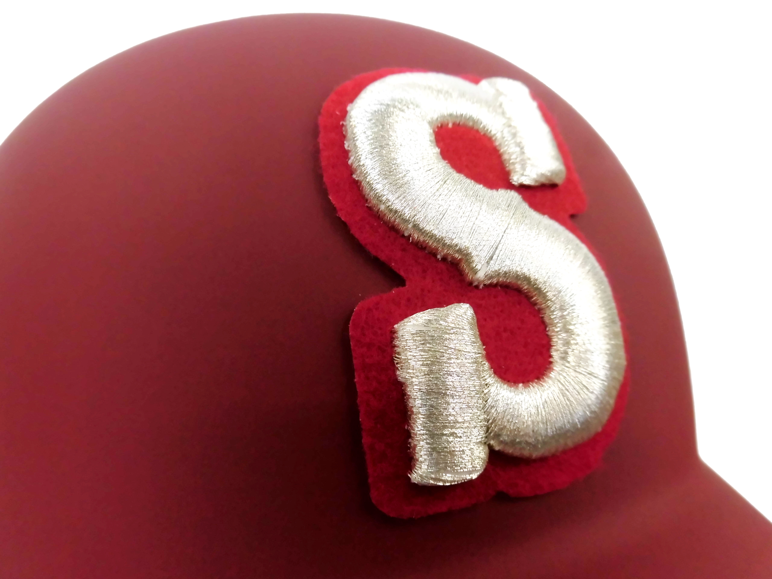 Close-up of red plush fabric with a metallic silver curved embroidery detail.