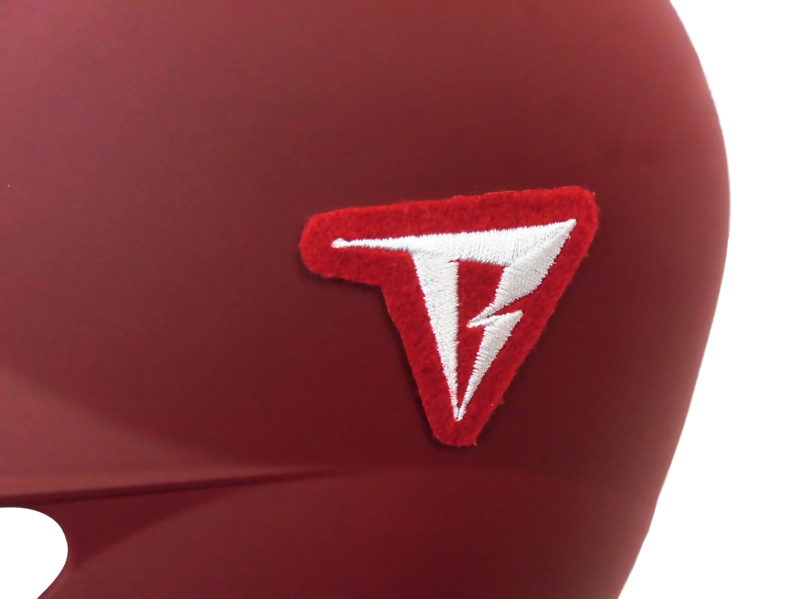 Close-up of maroon fabric with a small red and white embroidered patch partially visible on the right side