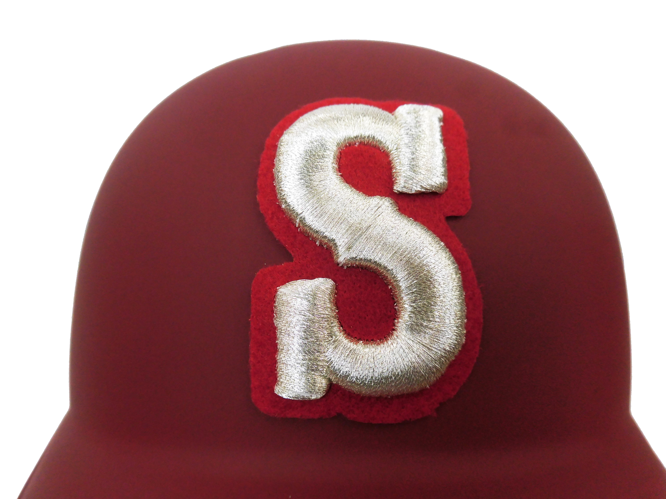 Close-up of a red circular badge with a metallic gold ribbon loop attached to it.